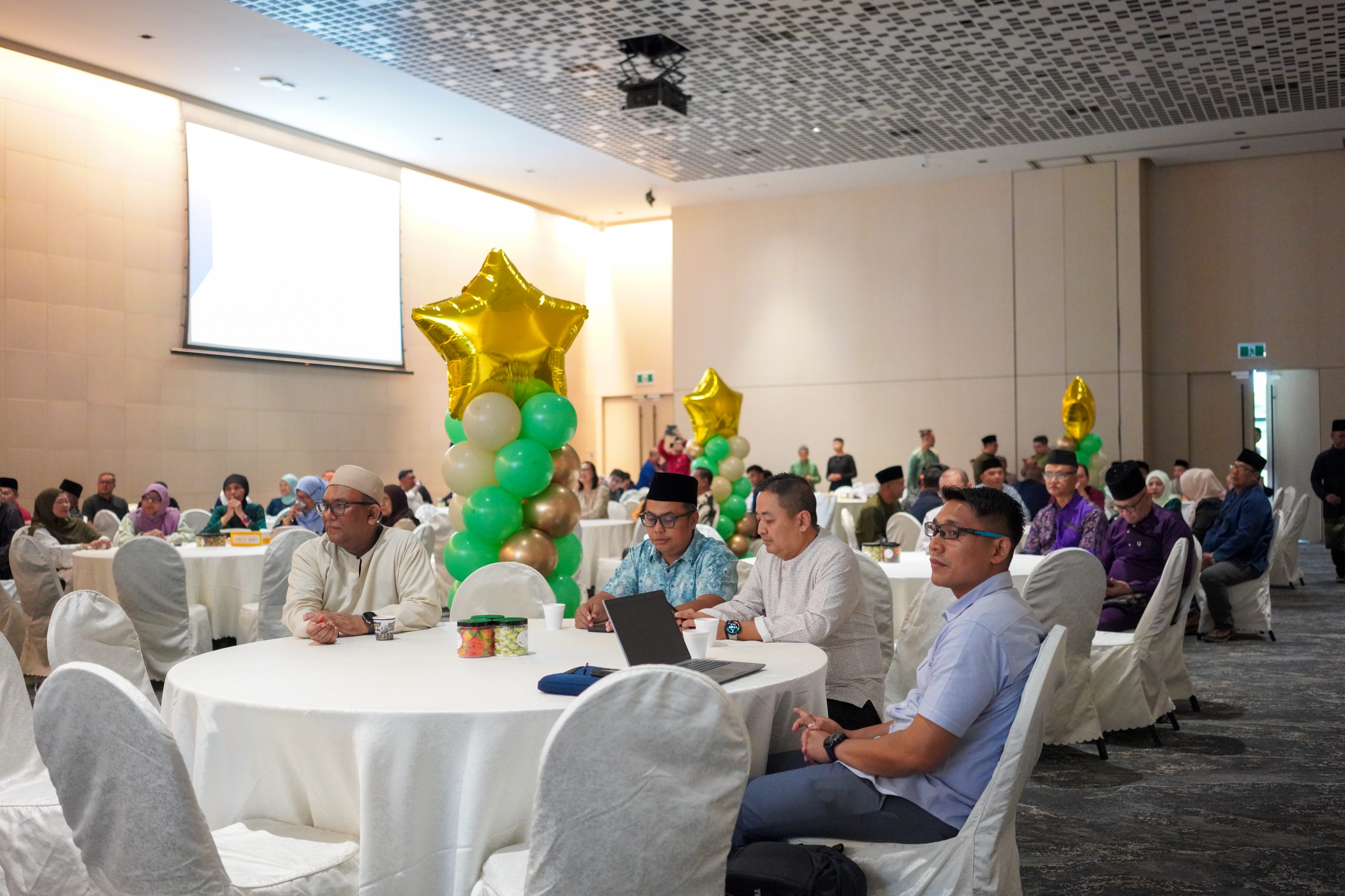 Guests seated at round tables listening to the proceedings of the Annual General Meeting.
